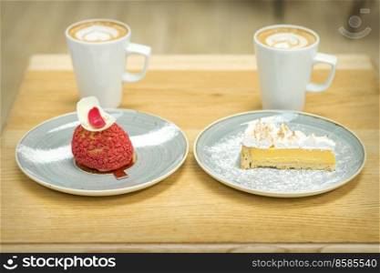 Two white cups of coffee with different pieces of cakes in saucers on the wooden table. Cups of coffee with pieces of cakes