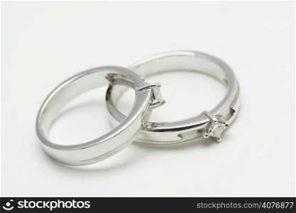 Two white gold wedding rings on silver background