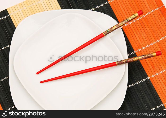 Two white plates with red chopsticks