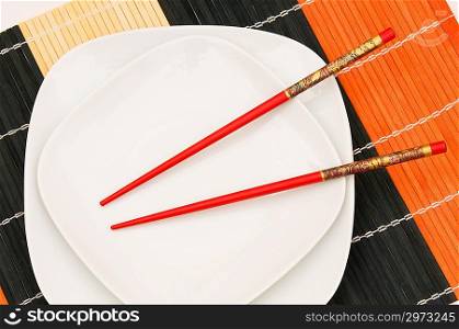 Two white plates with red chopsticks