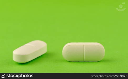 Two white tablet on a green background. A photo close up