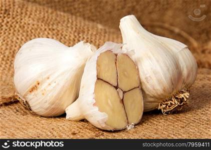 Two whole and half head of garlic on sackcloth