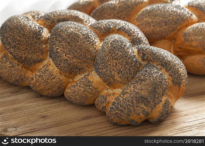 Two whole fresh Challah breads with poppy seeds