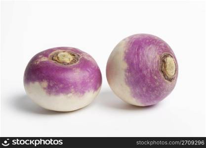 Two whole purple headed turnips on white background