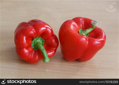 Two whole red peppers on a table