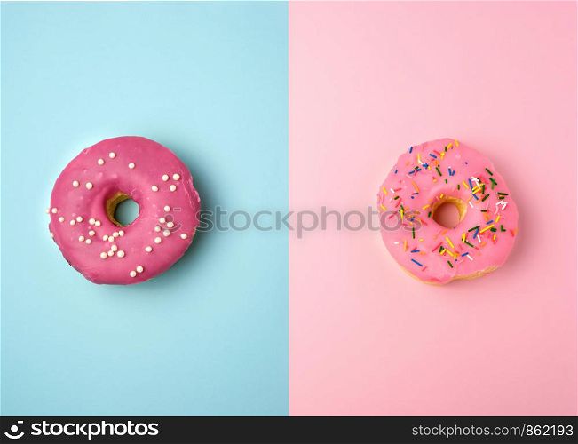 two whole round pink donuts with colored sprinkles lie on a blue-pink background, top view, pastel colors