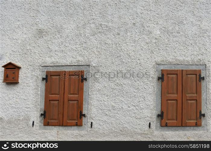 Two windows closed shuttered on stone wall