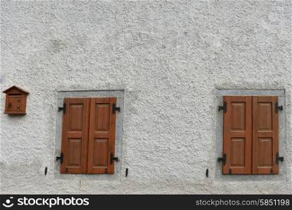 Two windows closed shuttered on stone wall