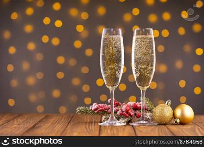 Two wine glasses with bubbly champagne, fir branch with decor on background of blurry sparkling lights. Happy New Year holiday greeting card, banner, header with copy space 