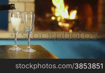 Two wine glasses with champagne on table and fireplace in background. Copy space