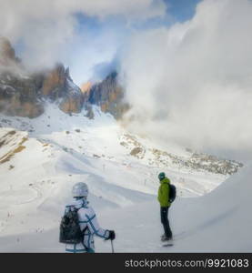 Two winter sports enthusiasts look away from the camera at the cloud covered impressive mountains of the Italian dolomites in South Tyrol. Two winter sports enthusiasts in the cloud covered mountains of the dolomites in South Tyrol