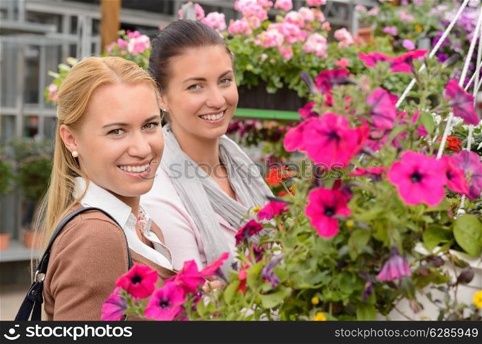 Two woman customers in garden center standing between colorful flowers