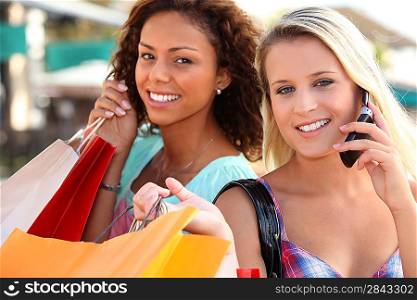 Two woman on mobile phones holding shopping bags