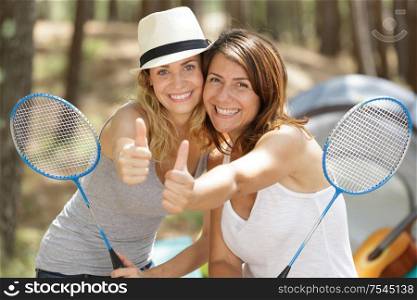 two woman playing badminton outdoors