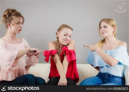 Two woman pointing at her female friends accusing for something she have not done.. Two woman pointing at her female friend