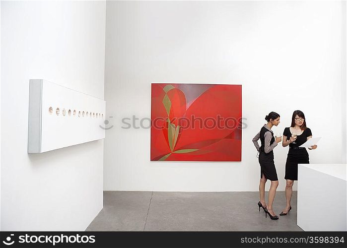 Two woman standing next to wall paintings