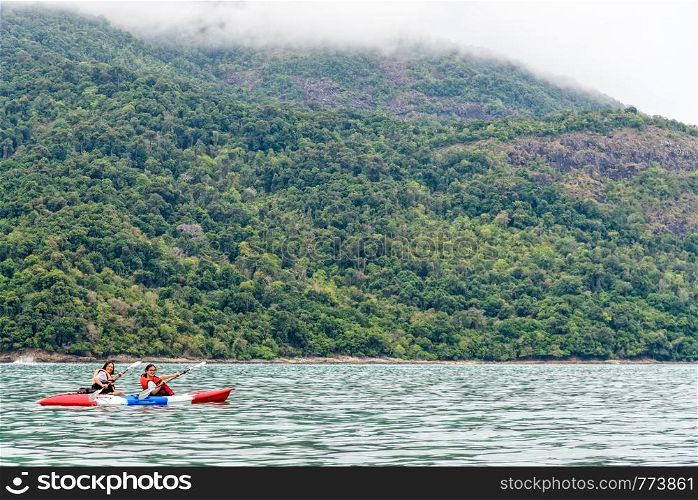 Two woman tourists are mother and daughter. Travel by boat with a kayak happy on the sea in the morning of summer at Ko Adang island is the background, Tarutao National Park, Satun, Thailand. Two woman are kayaking on the sea, Thailand