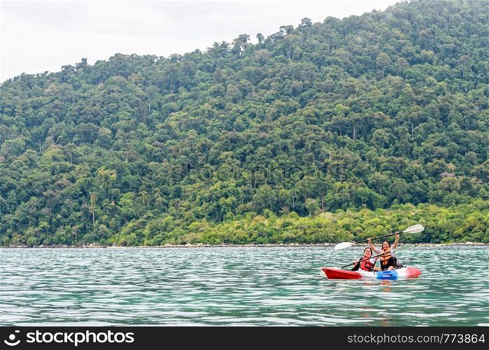 Two woman tourists are mother and daughter. Travel by boat with a kayak happy on the sea in the morning of summer at Ko Adang island is the background, Tarutao National Park, Satun, Thailand. Two woman are kayaking on the sea, Thailand