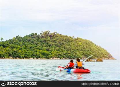 Two woman tourists are mother and daughter travel by boat with a kayak under sunlight of summer at Ko Lipe enjoy the beautiful nature the sea and island in morning, Tarutao National Park, Satun, Thailand. Mother and daughter travel by kayak at Ko Lipe, Thailand