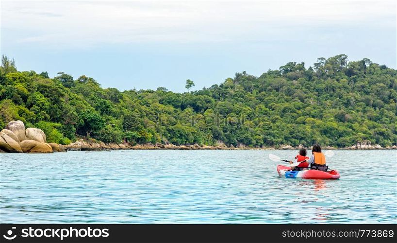 Two woman tourists are mother and daughter. Travel by boat with a kayak happy on the sea in the morning of summer at Ko Lipe island is the background, Tarutao National Park, Satun, Thailand. Two woman travel by kayak at Ko Lipe island, Thailand