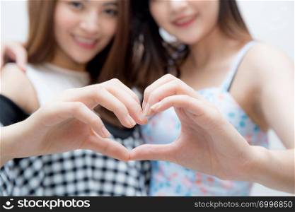 Two woman twins showing heart shape with hands closeup.