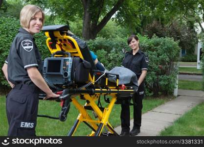 Two women ambulance workers with stretcher in rural area