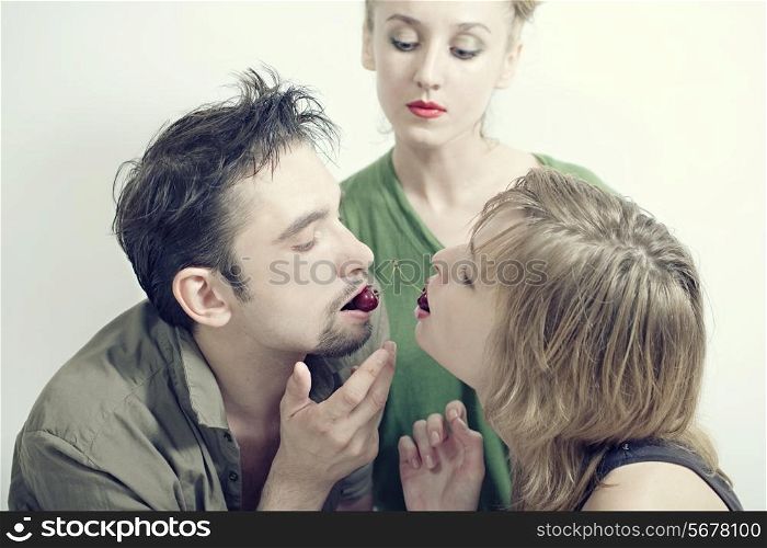 Two women and one man with the red ripe cherries closeup