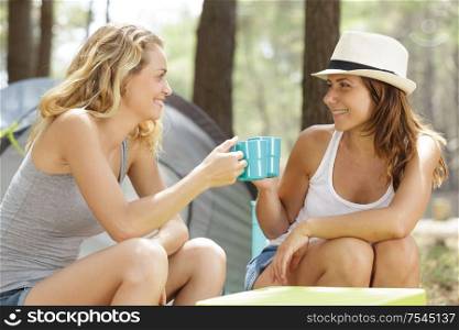 two women are drinking coffee outdoors