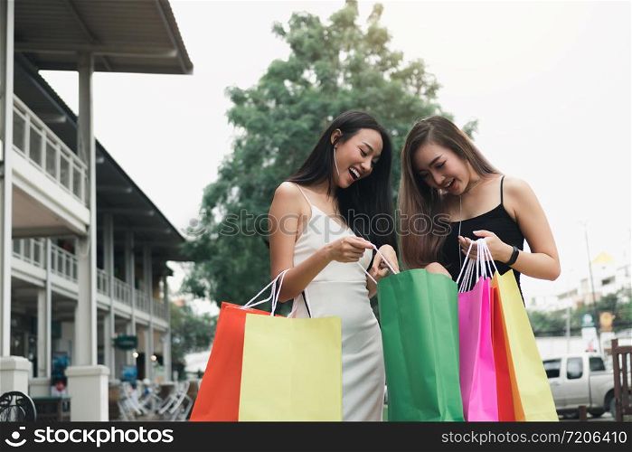 Two women are looking at a shopping bag.