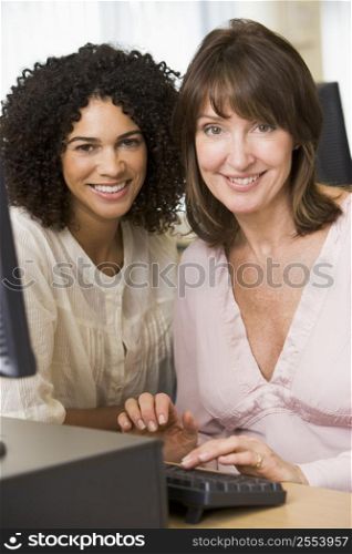 Two women at a computer terminal typing (high key)