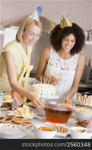 Two women at party setting out food smiling