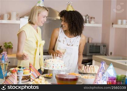 Two women at party standing by food table smiling