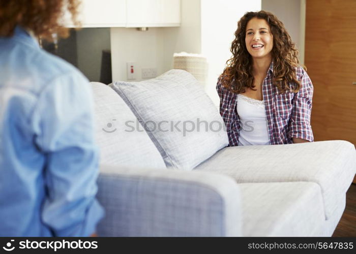 Two Women Carrying Sofa As They Move Into New Home