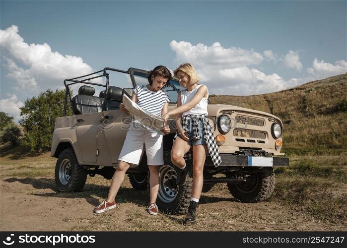 two women checking map together while traveling by car