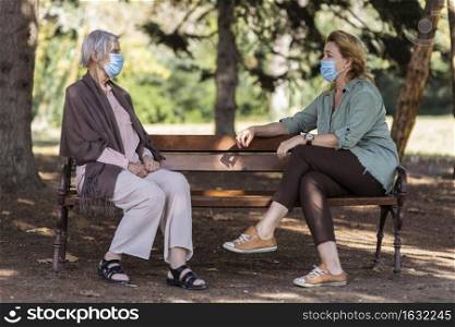 two women conversing with medical masks outdoors nursing home