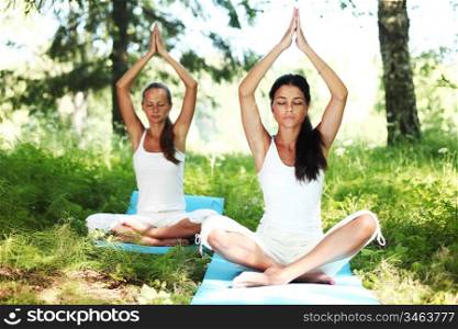 Two women doing yoga in the park