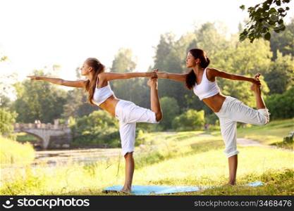 Two women doing yoga in the park
