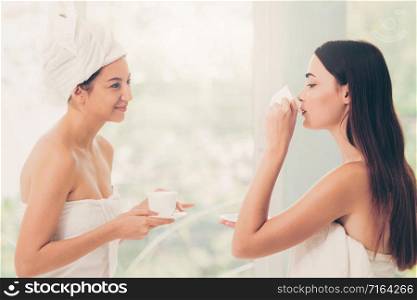 Two women drinking tea or herbal drinks while having conversation in luxury day spa. Wellness, leisure and healthcare concept.. Two women drinking tea in luxury day spa.