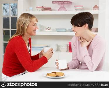 Two Women Enjoying Hot Drink In Kitchen