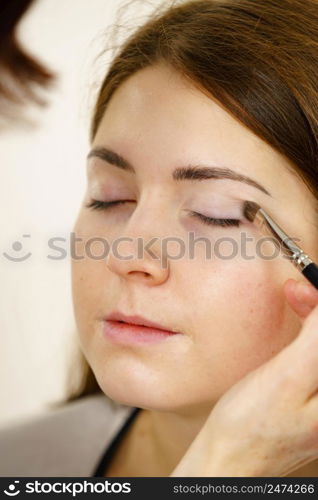 Two women, face painting. Makeup artist applying shadows to model eye. Cosmetic beauty procedures, make up stage.. Makeup artist apply make up