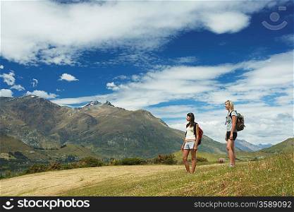 Two women hiking in hills near mountains