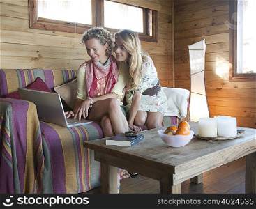 two women in a beach house, using laptop