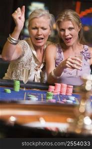 Two women in casino playing roulette and smiling (selective focus)