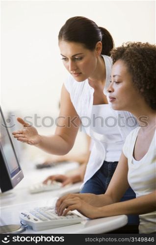 Two women in computer room where one is assisting the other