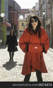 Two women in jackets on a street. Sunlight
