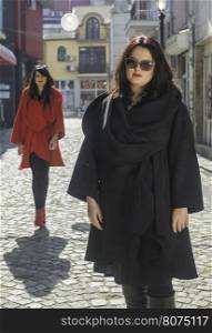 Two women in jackets on a street. Sunlight