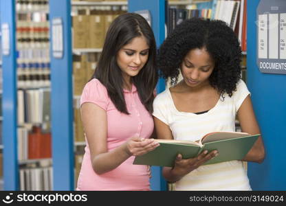 Two women in library reading book (depth of field)