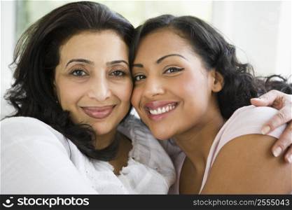 Two women in living room embracing and smiling (high key)