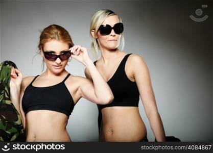 Two women in military clothes and sunglasses army girls on gray background