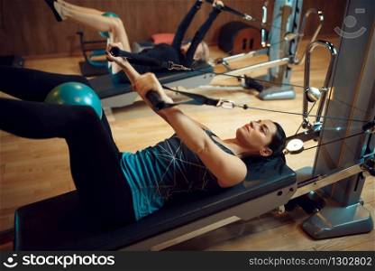 Two women in sportswear, pilates training with balls on exercise machines in gym. Fitness workuot in sport club. Athletic female person, aerobics indoor, body stretching. Pilates training with balls on exercise machines